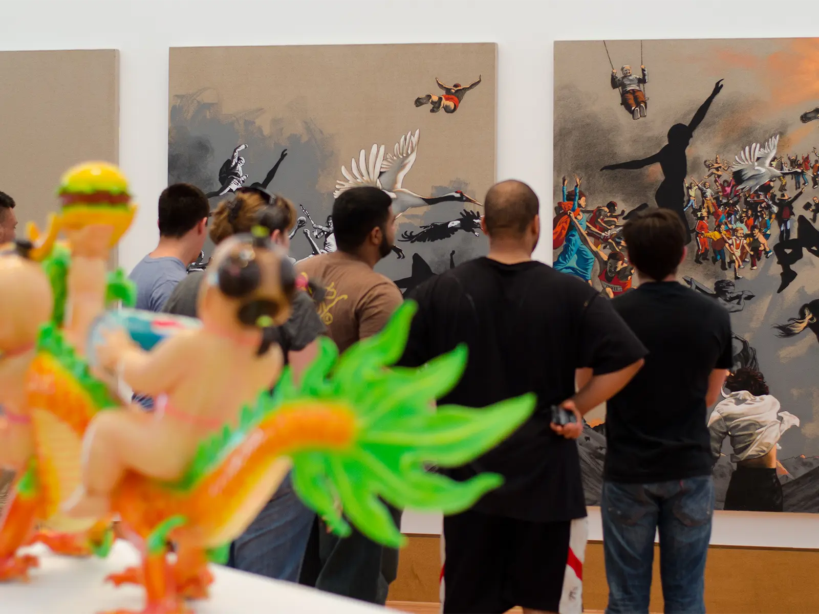 Students observe a triptych of artwork, with an Asian glass sculpture depicting a child riding a dragon in the foreground